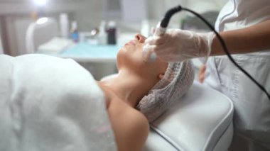 Güzel, beyaz bir kadın, bir kozmetoloji kliniğinde yüz gerdirme ameliyatı oluyor. Ameliyat değil, donanım kozmetolojisi, profesyonel cilt bakımı, güzellik tedavi konsepti. 4K görüntü