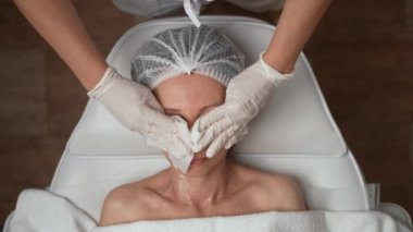 Kozmetik uzmanı yüz temizleme ameliyatı ve 40 'lı yaşlardaki orta yaşlı kadın derisini aşağıdaki tedaviler ve donanım prosedürleri için hazırlıyor. Cerrahi olmayan, donanım kozmetolojisi, yaş gençleştirme karşıtı konsept