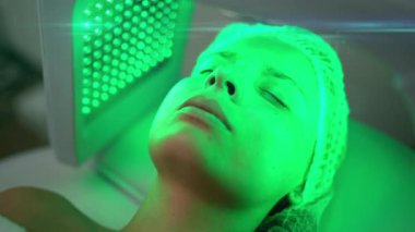 Genç bir kadının portresi, güzellik salonunda yeşil LED ışık tedavisi görüyor. Güzellik, sağlık ve sağlık konsepti. Kozmetik ve cilt bakımı. Yüksek kalite 4k görüntü