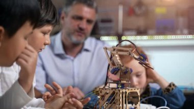 BTMM eğitimi. Robot mühendisliği sınıfından bir ders. Bir grup farklı ilkokul çocuğu öğretmenleriyle elektronik robotların nasıl monte edileceğini ve nasıl çalıştırılacağını tartışıyor..