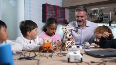 Coşkulu erkek öğretmen çok ırklı okullara robotik dersi veriyor. Fütürist teknolojiler bilim sınıfı. BTMM eğitim kavramı