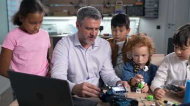 Robot mühendisliği sınıfında hevesli erkek öğretmen öğrenme teknolojisi olan bir grup çok ırklı öğrenci. Fütüristik Teknolojiler Bilim Sınıfı. BTMM Eğitim Konsepti.