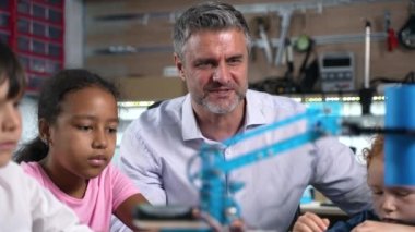 Robot mühendisliği dersinde yaptıkları robot elektrik makinesini izleyen hevesli öğretmenlere ve çeşitli çocuklara yakın çekim. Fütürist teknolojiler bilim sınıfı. STEM 