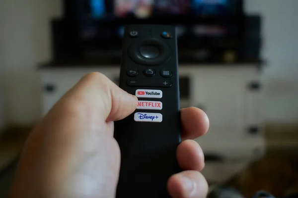 A hand holding a smart TV remote control. Streaming service google tv andoid tv