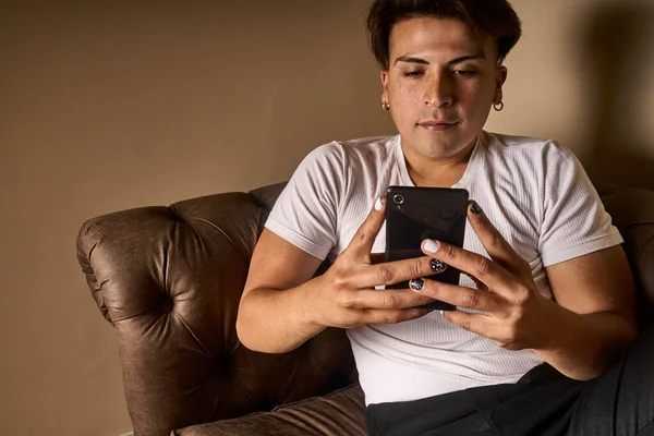 latin man on a sofa using a telephone black and white painted nails