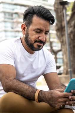 Kentsel çevrede cep telefonuna bakan Latin adamın yakın çekimi