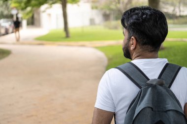 Sırt çantalı Latin bir adamın yola bakarken çekilmiş fotoğrafı.