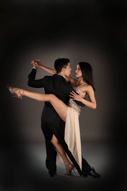 Latin kadın ve Asyalı erkek tango dansı yapıyor. Stüdyo çekimi