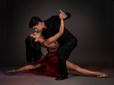 Tango salonu tangosu. Latin bir çift kadın ve Asyalı bir adam. Stüdyo, siyah arka plan çekmiş.