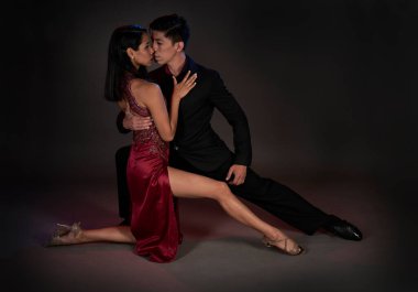Tango salonu tangosu. Latin bir çift kadın ve Asyalı bir adam. Stüdyo, siyah arka plan çekmiş.