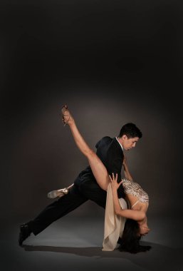 Tango salonu tangosu. Latin bir çift kadın ve Asyalı bir adam. Stüdyo, siyah arka plan çekmiş.