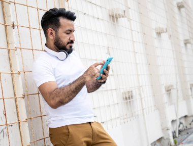 Sakallı Latin bir adam, cep telefonuna mesaj yazıyor.