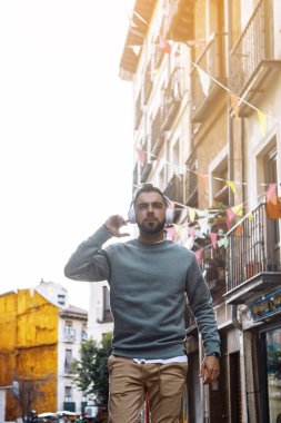 Adam kulaklıkla müzik dinlemek için akıllı bir telefon kullanıyor.