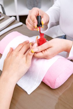 Manikürcü elleri, müşterilerinin tırnaklarına oje sürmesi.