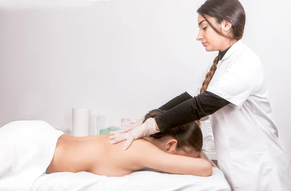 Sedyede yatan genç bir kadın fizik tedavi merkezinde sırt masajı yaptırıyor.. — Stok fotoğraf