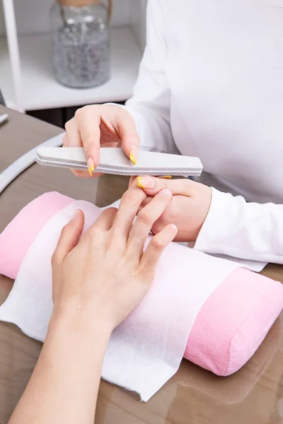 manicurist filing and shaping nails, with file