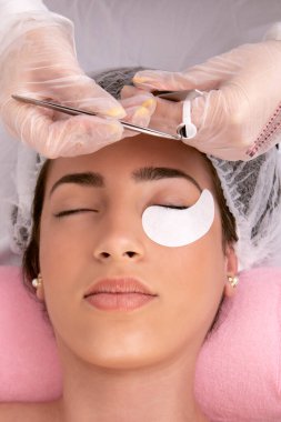 Güzellik uzmanı kirpikleri müşteri gözünün alt kısmına yerleştirmek için alıyor. Yüksek kalite fotoğraf