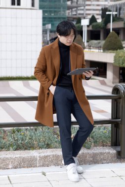 İş merkezinin dışındaki Asyalı adam tabletini, iş konseptini kullanıyor. Yüksek kalite fotoğraf