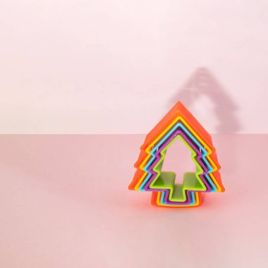 Açık pembe arka planda renkli Xmas ağacı. Minimalist Noel dekorasyonu konsepti. Kopya alanı olan yeni yıl kompozisyonu. Kış tatili fikri.