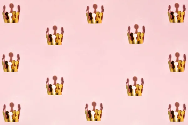 パステルライトピンクの背景に金色の冠で作られたパターン 最小限の成功の概念 コピースペースと創造的な勝利の組成 — ストック写真