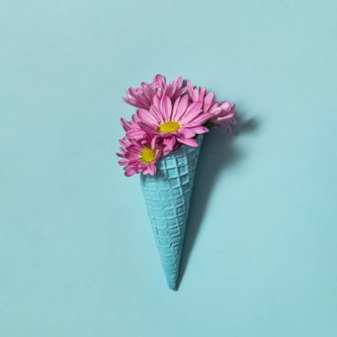 Pastel açık mor çiçek, mavi arka planda dondurmalı mavi koni. Yaratıcı çiçek konsepti. Asgari doğa ve besin bileşimi.