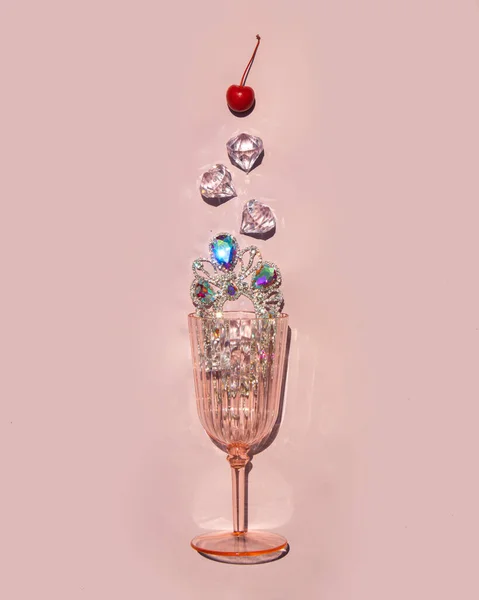 淡いパステルカラーの背景にピンク色のガラスに宝石 ダイヤモンド チェリーが入ったおいしいドリンク 創造的な飲料の概念 最小限の豊かな風味組成 夏の晴れた日のアイデア ストック画像