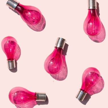Creative innovation concept. Pink light bulbs on pastel bright background. Minimalistic electricity composition.