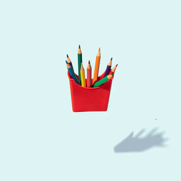 Minimal composition with colored pencils on pastel bright blue background. Back to school idea. Creative education concept. Fast food inspiration.