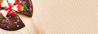 Çilekli ve çikolatalı pasta panoraması, ahşap arka planda kesilmiş ve fotokopi alanı var..
