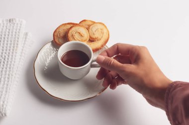 Kadın eli kahvaltının yanında sıcak çikolata ve beyaz arka planlı palmeritalar.