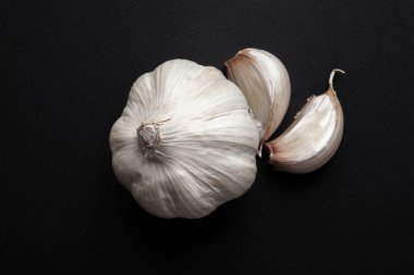 Sarımsak kafalar ve siyah arka planda sarımsak karanfilleri. sağlıklı malzemeler gıda konsepti.