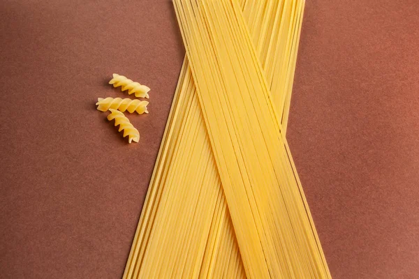 Pişmemiş spagetti ve kahverengi arka planda fushilli.