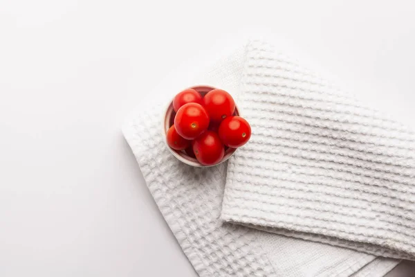 top view of cherry tomatoes in bowl on white background with copy space