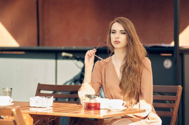 Güzel genç bir kadın güneşli bir günde kahve molası verir.