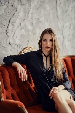 Kısa elbiseli güzel bir kadın kanepede oturuyor.