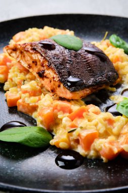 Yakından bakınca, bulguru ve tatlı patatesle servis edilen kızarmış somon bifteği.