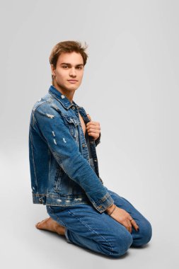 Kot elbiseli genç adam ctudio 'da yerde oturuyor.