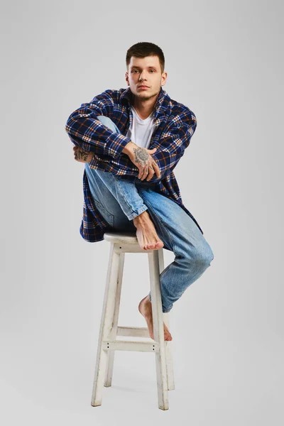 Uzun Tahta Sandalyede Oturan Çıplak Ayaklı Kot Pantolonlu Genç Adamın — Stok fotoğraf
