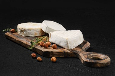 Cheese platter. Assortment of brie and camembert cheese on wooden cutting board.