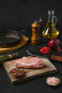 Çiğ biftek kemiği ve siyah arka planda yemek pişirmek için malzemeler.