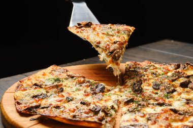 Spatula üzerinde mantarlı ince hamurlu pizza.