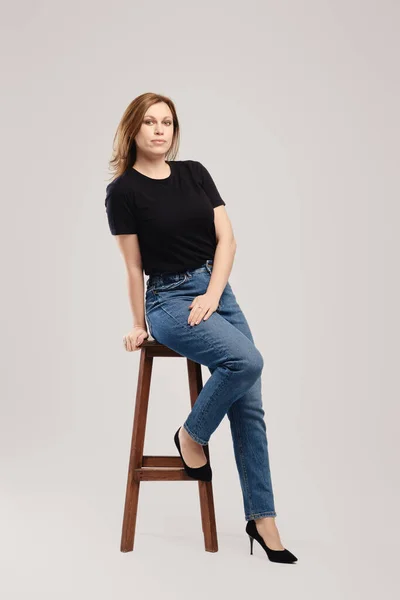 Jonge Vrouw Zwart Shirt Jeans Poseren Hoge Houten Stoel Grijze — Stockfoto