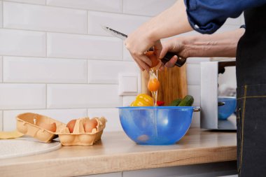 Omlet yapmak için yumurta kıran bir adamın yakından görüntüsü.