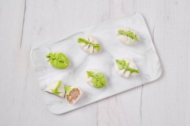 Domuz etiyle doldurulmuş donmuş hamur köfteleri ve mermer servis tabağına konmuş provenkal otlar.