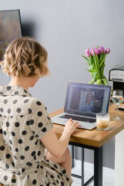 İş ortağına bilgisayar kullanarak video görüşmesi yapan bir kadının arka planda sanal internet sohbeti ile ekrana bakması.