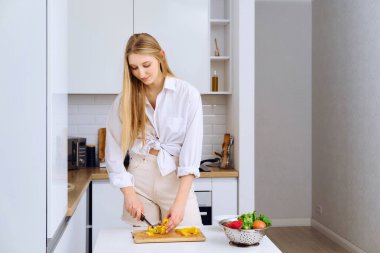 Genç bir kadın tahta kesme tahtasındaki salata için dolmalık biber kesti. Doğal malzemeler, çiğ vegan sebzeler..