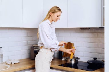 Aktif genç bir kadın kaynar suya spagetti koyar.
