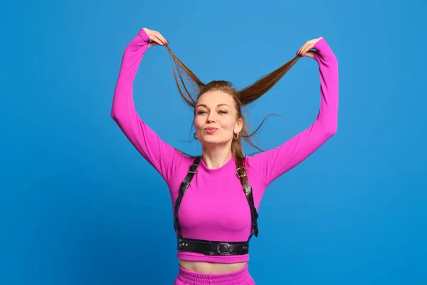 Glückliche Frau Lila Strickanzug Spielt Mit Haaren Vor Blauem Studiohintergrund — Stockfoto