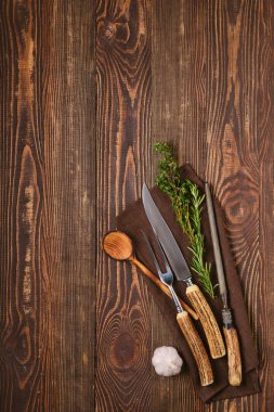 Biftek çatalı, bıçak ve bileyici kahverengi ahşap arka planda.
