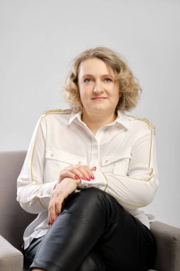 Kollarını kavuşturmuş beyaz gömlekli kendinden emin yaşlı bir kadının stüdyo portresi.